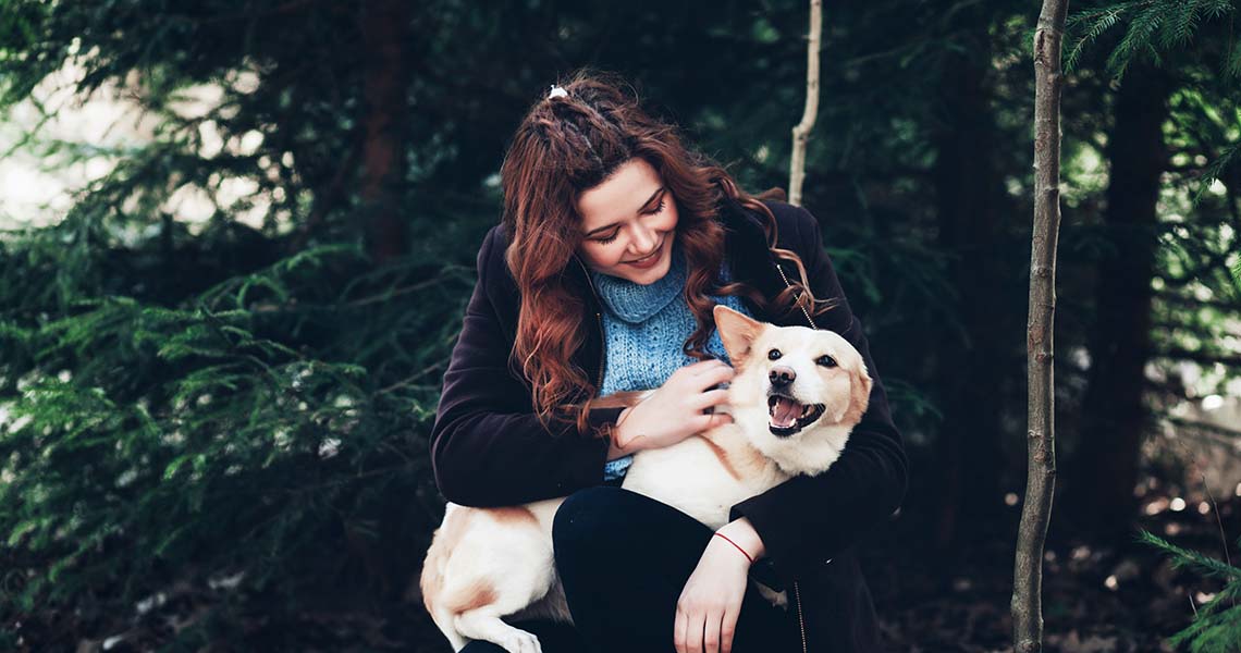 Glad kvinna som håller hund i famnen