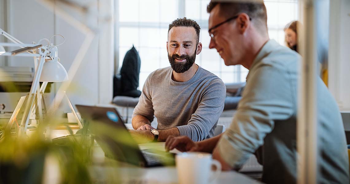 Två programmerare på kontor som tittar i laptop