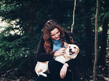 Glad kvinna som håller hund i famnen