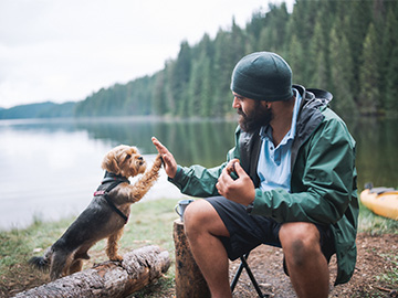 Man som high fivear hund på strand