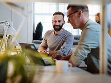 Två programmerare på kontor som tittar i laptop